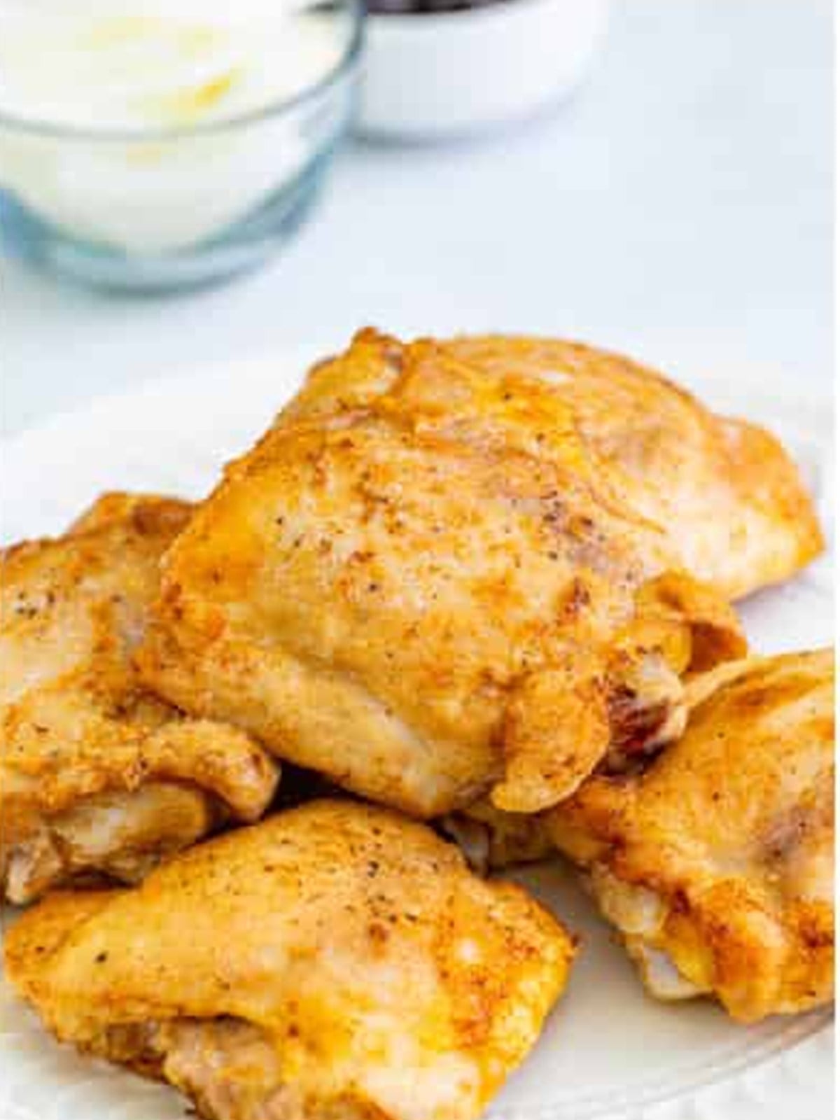 Golden seared chicken thighs on a white plate for chicken cacciatore.