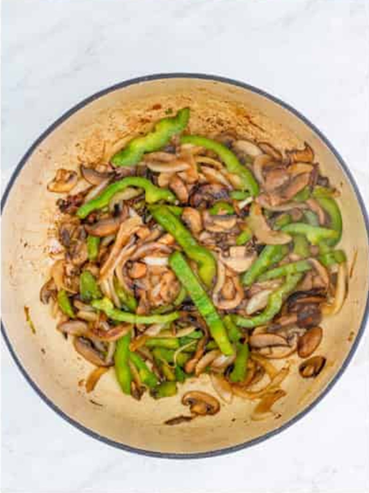 Onion, green pepper, and mushrooms sauteing in a dutch oven for chicken cacciatore.