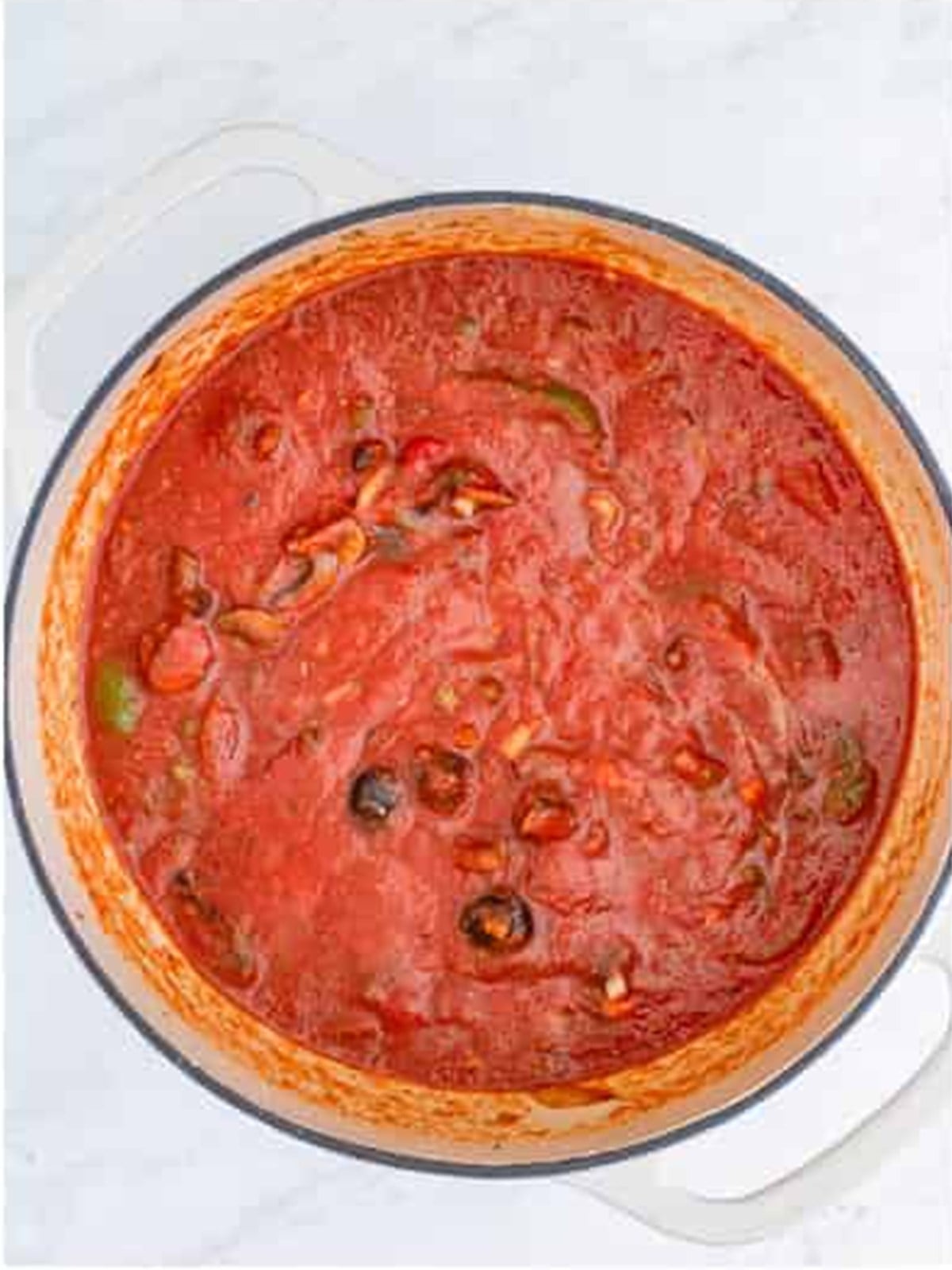 Chicken cacciatore sauce stirred together in a dutch oven.