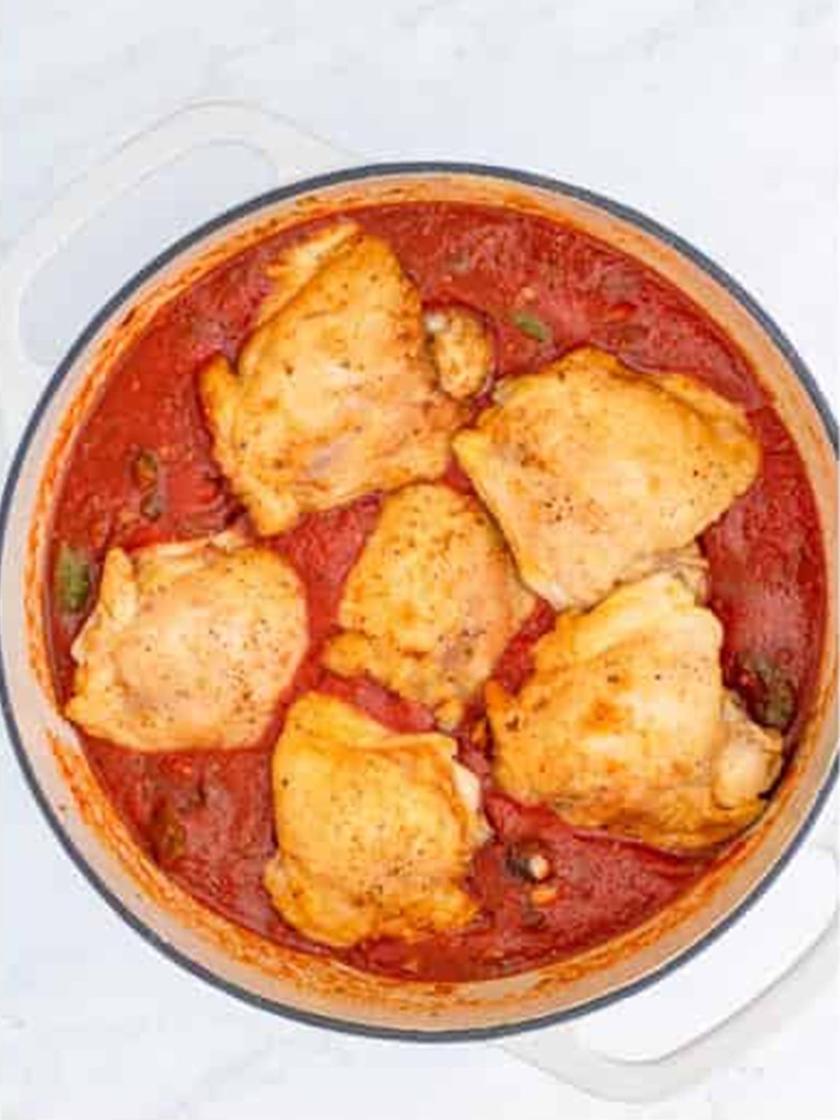 Seared chicken thighs nestled back into the tomato sauce for chicken cacciatore.