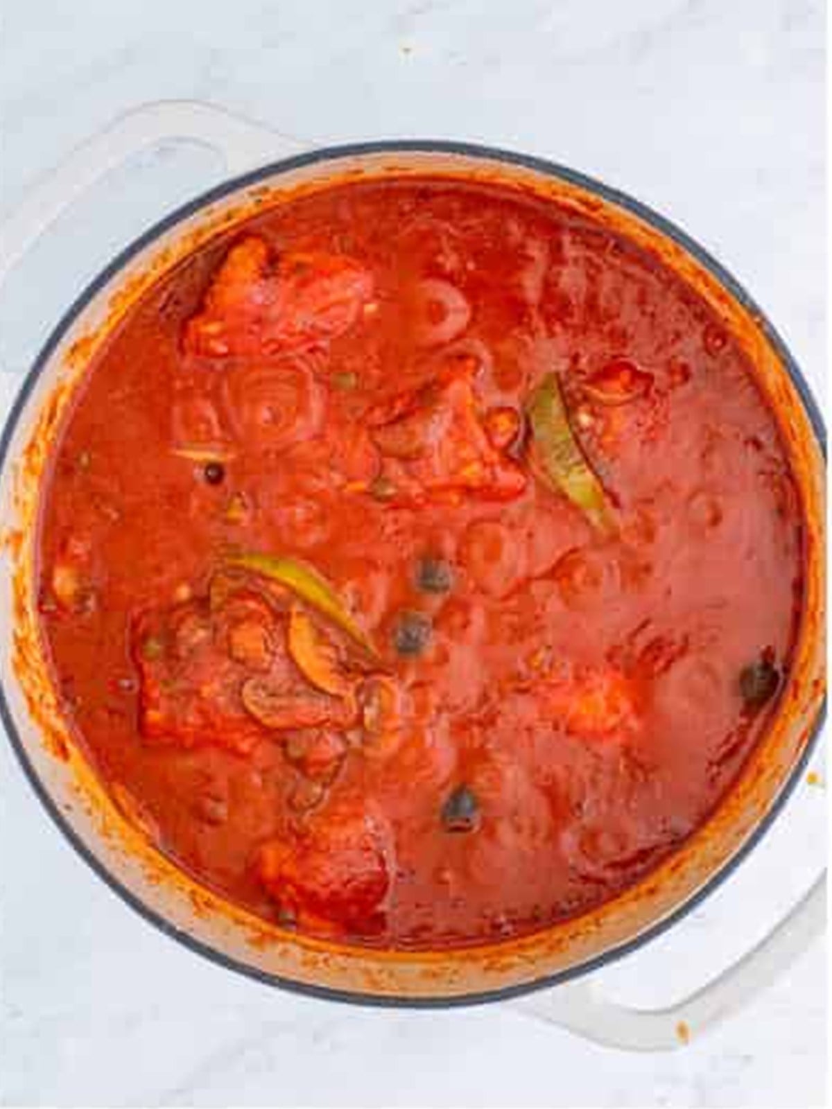 Finished chicken cacciatore simmering in rich tomato sauce in a dutch oven.