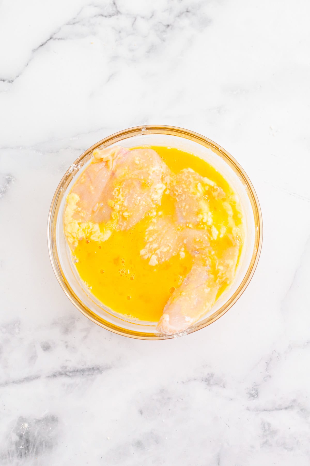 A bowl of beaten egg for coating the Cobb Salad chicken.