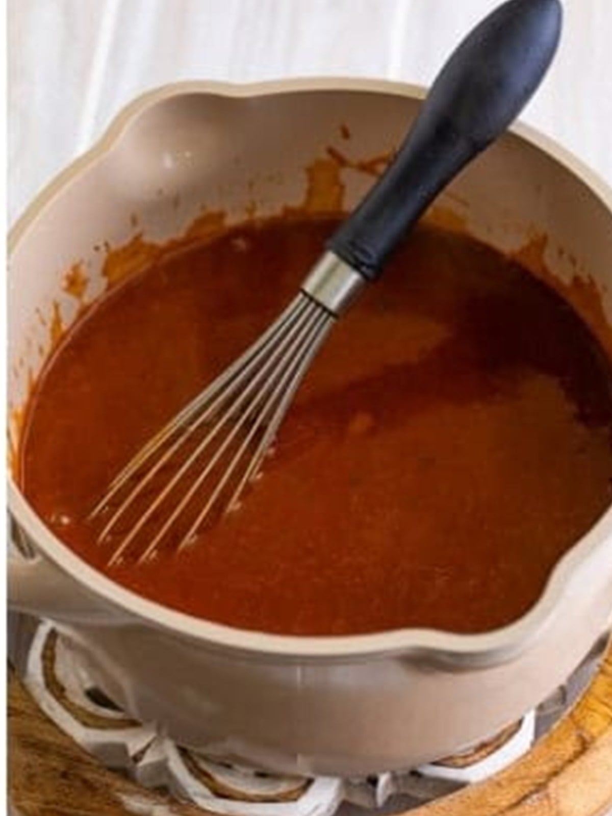 Smooth simmered homemade enchilada sauce whisked in a pot.