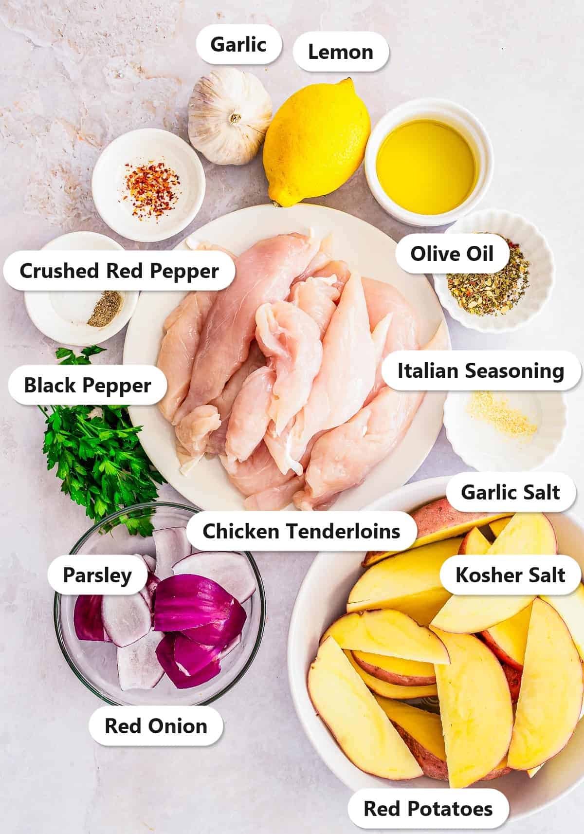 Labeled ingredients for chicken foil packets including chicken tenderloins, red potatoes, red onion, lemon, olive oil, garlic, Italian seasoning, garlic salt, kosher salt, crushed red pepper, black pepper, and parsley.