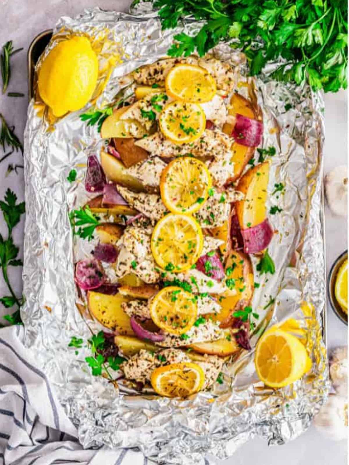 The baked Italian lemon chicken foil packet opened and garnished with fresh parsley.