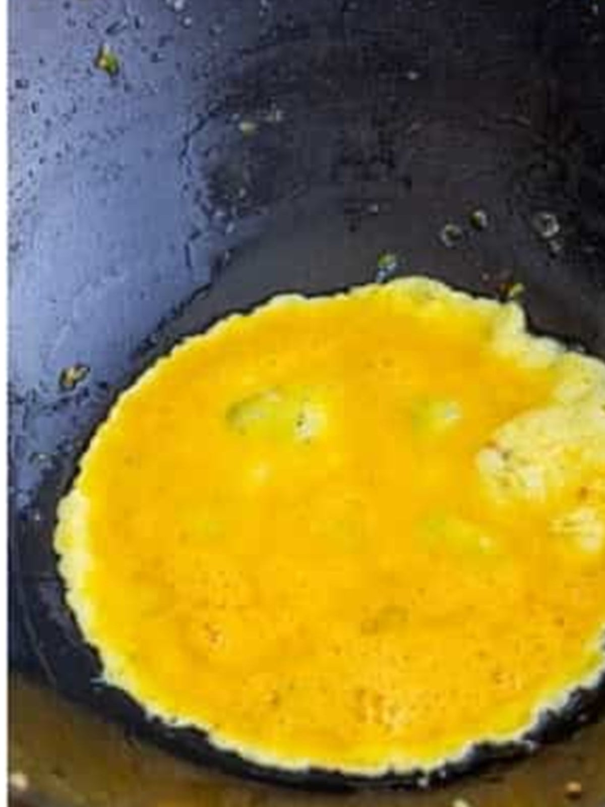 Scrambling beaten eggs in a wok