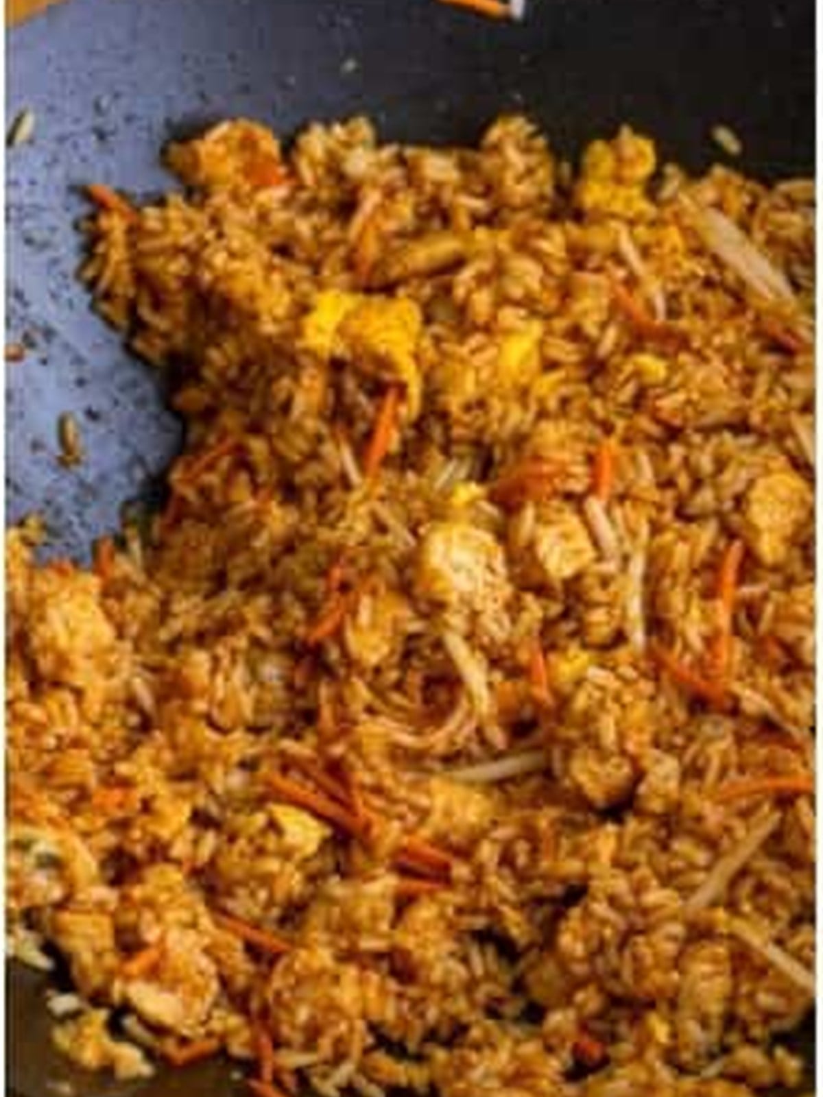 Chicken fried rice tossed with savory brown sauce in a wok