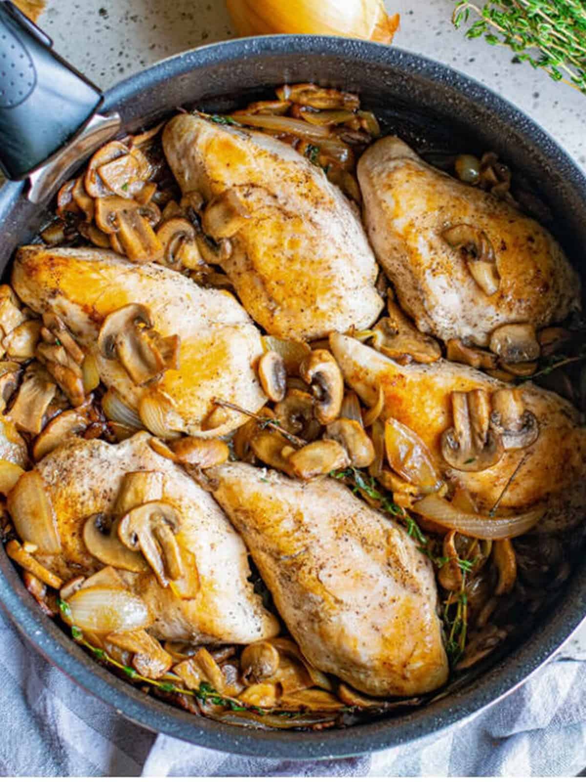 Chicken breasts returned to the skillet with sauteed mushrooms and onions.