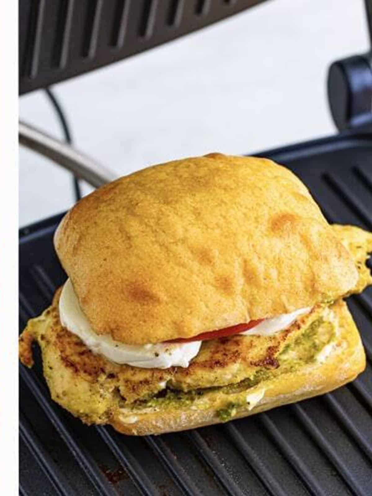 Chicken pesto sandwiches toasting in a panini press until golden.