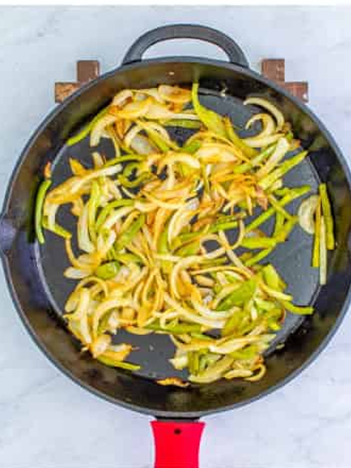 Bell pepper and onion sauteing in a skillet for chicken quesadillas.