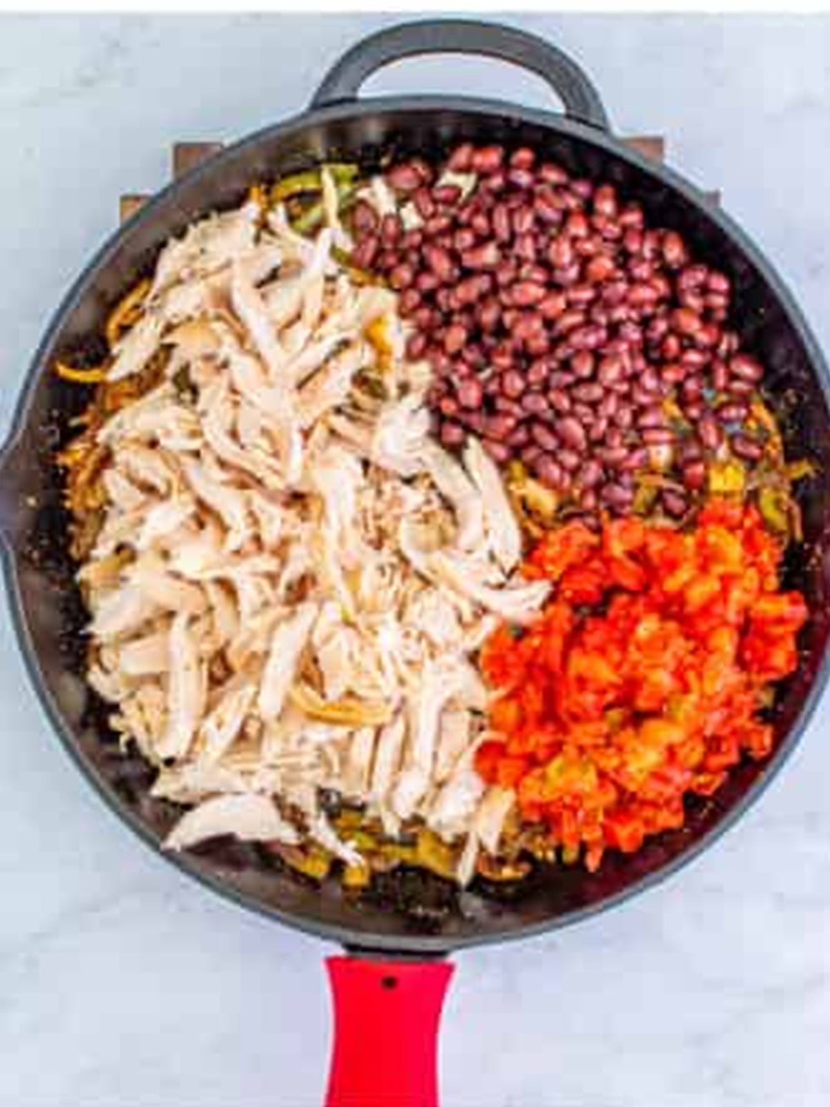 Shredded chicken, black beans, and tomatoes added to the skillet with taco seasoning.
