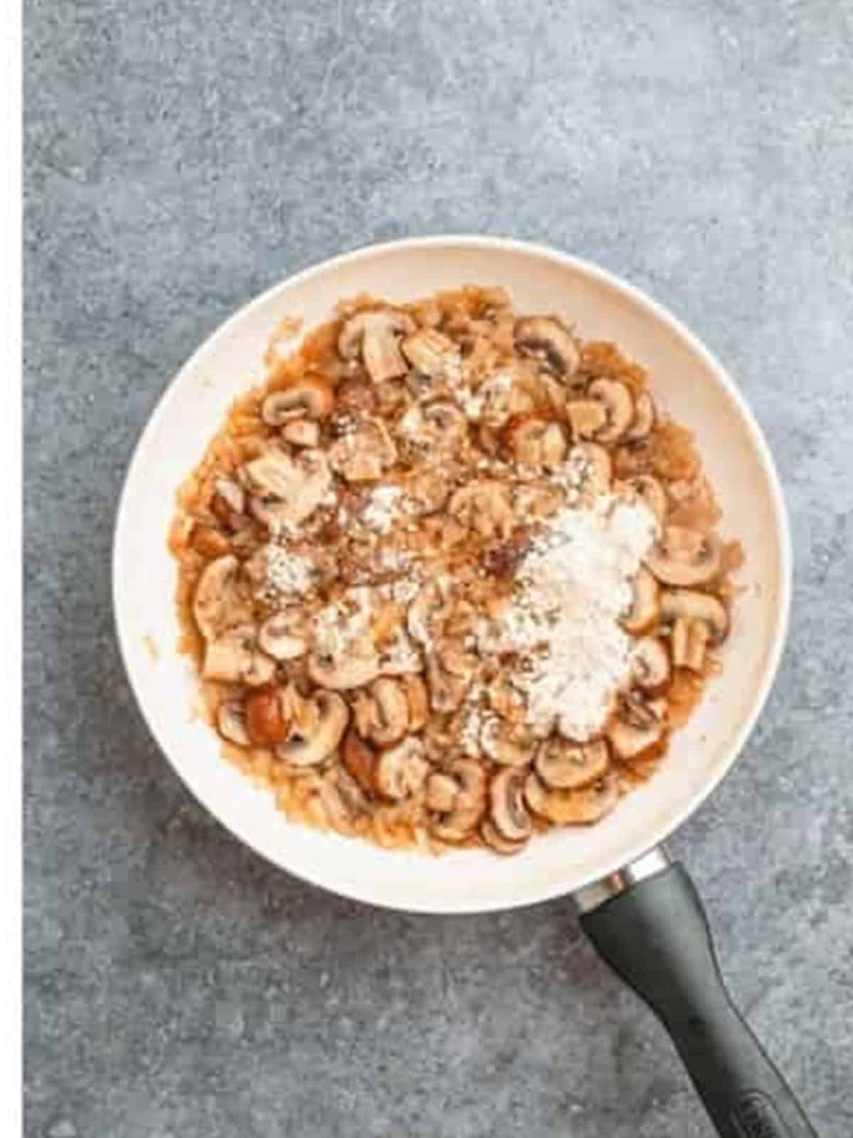 Onions and mushrooms cooked with flour in the skillet for chicken stroganoff.