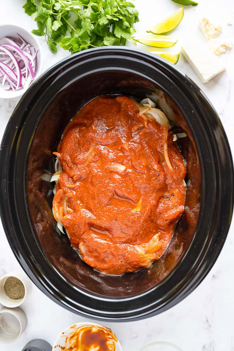 Blended tinga sauce poured over chicken and onions in the slow cooker.