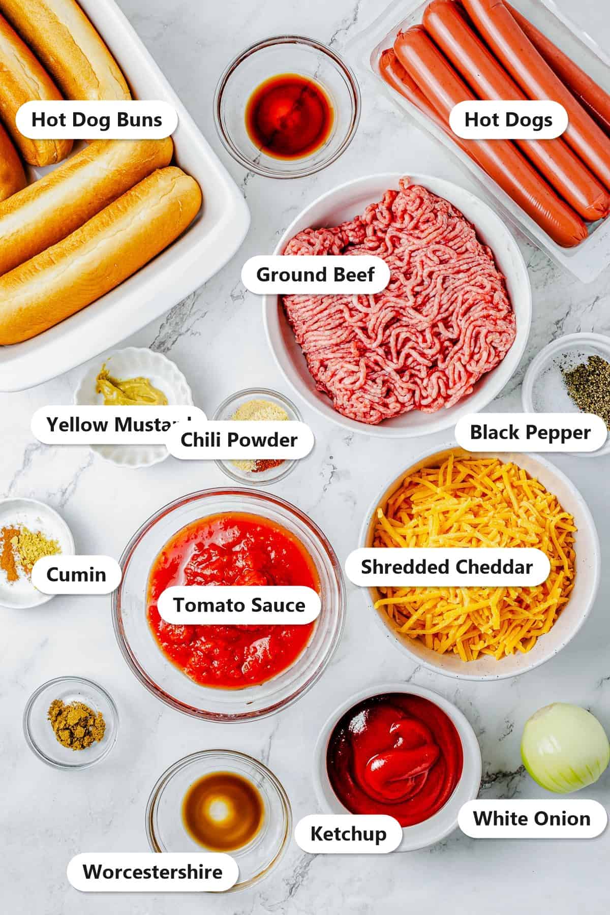Labeled ingredients for chili dogs including hot dogs, buns, ground beef, tomato sauce, ketchup, shredded cheddar, mustard, onion, and seasonings.