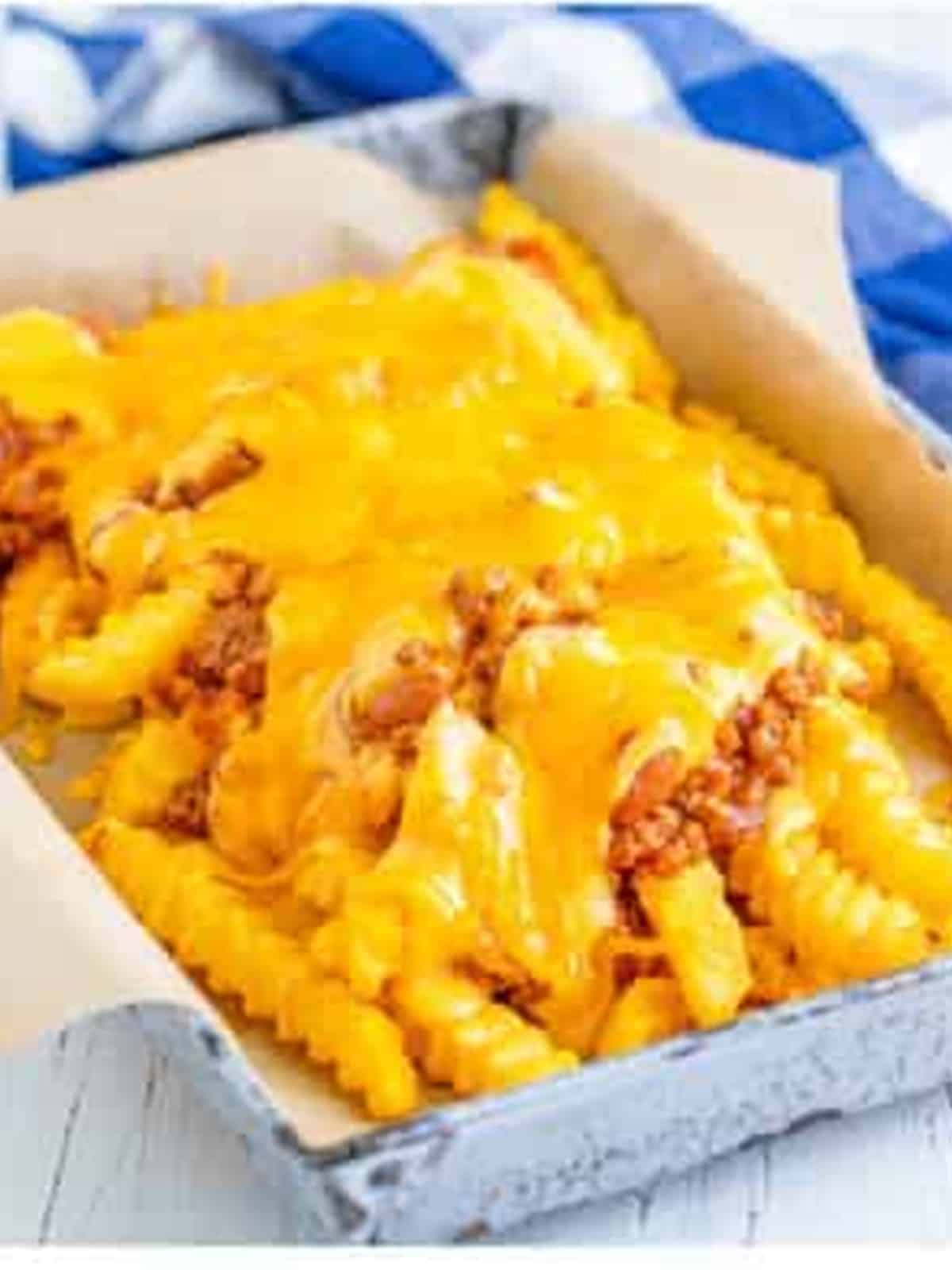Finished chili cheese fries topped with melted cheddar cheese and scallions.