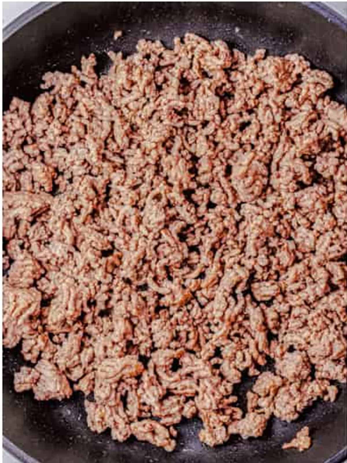 Ground beef browning in a skillet for homemade chili dog sauce.