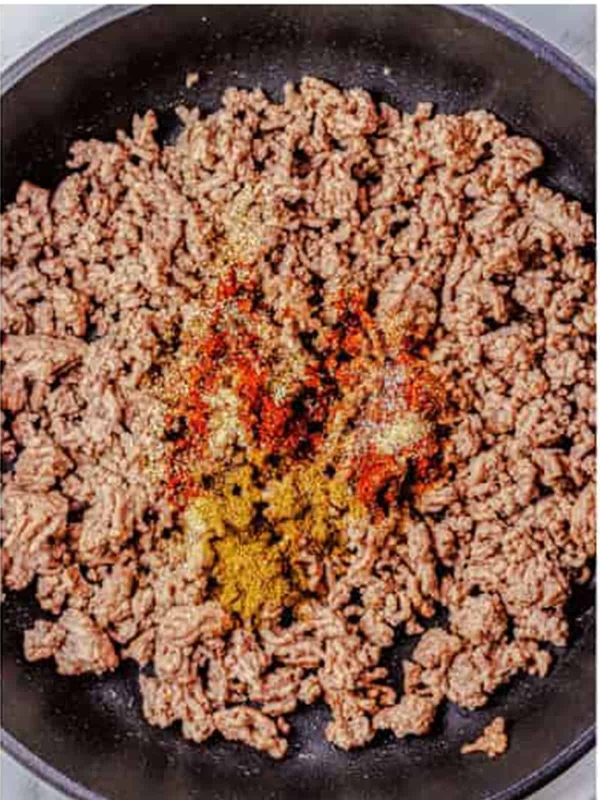 Chili powder, cumin, and seasonings stirred into browned ground beef.