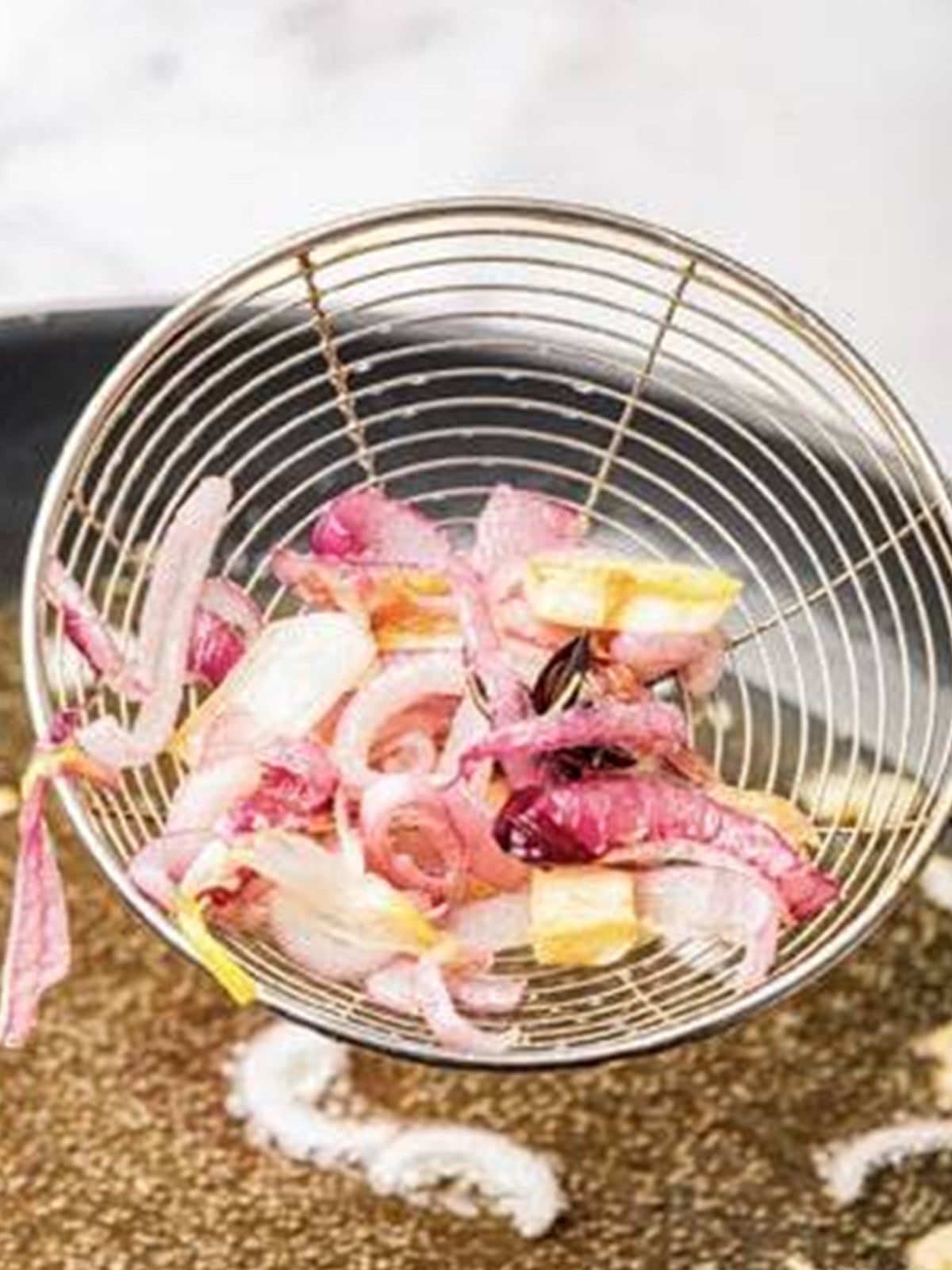 Straining the fried solids out of the hot infused oil for chili oil.