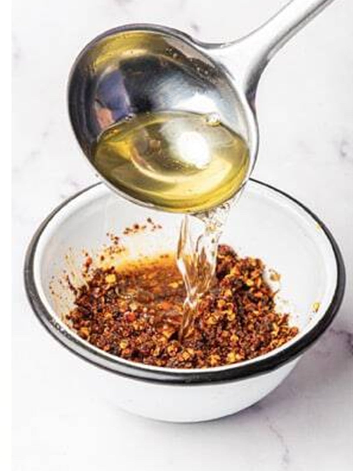 Pouring the hot infused oil over the chili flake and spice mixture for chili oil.