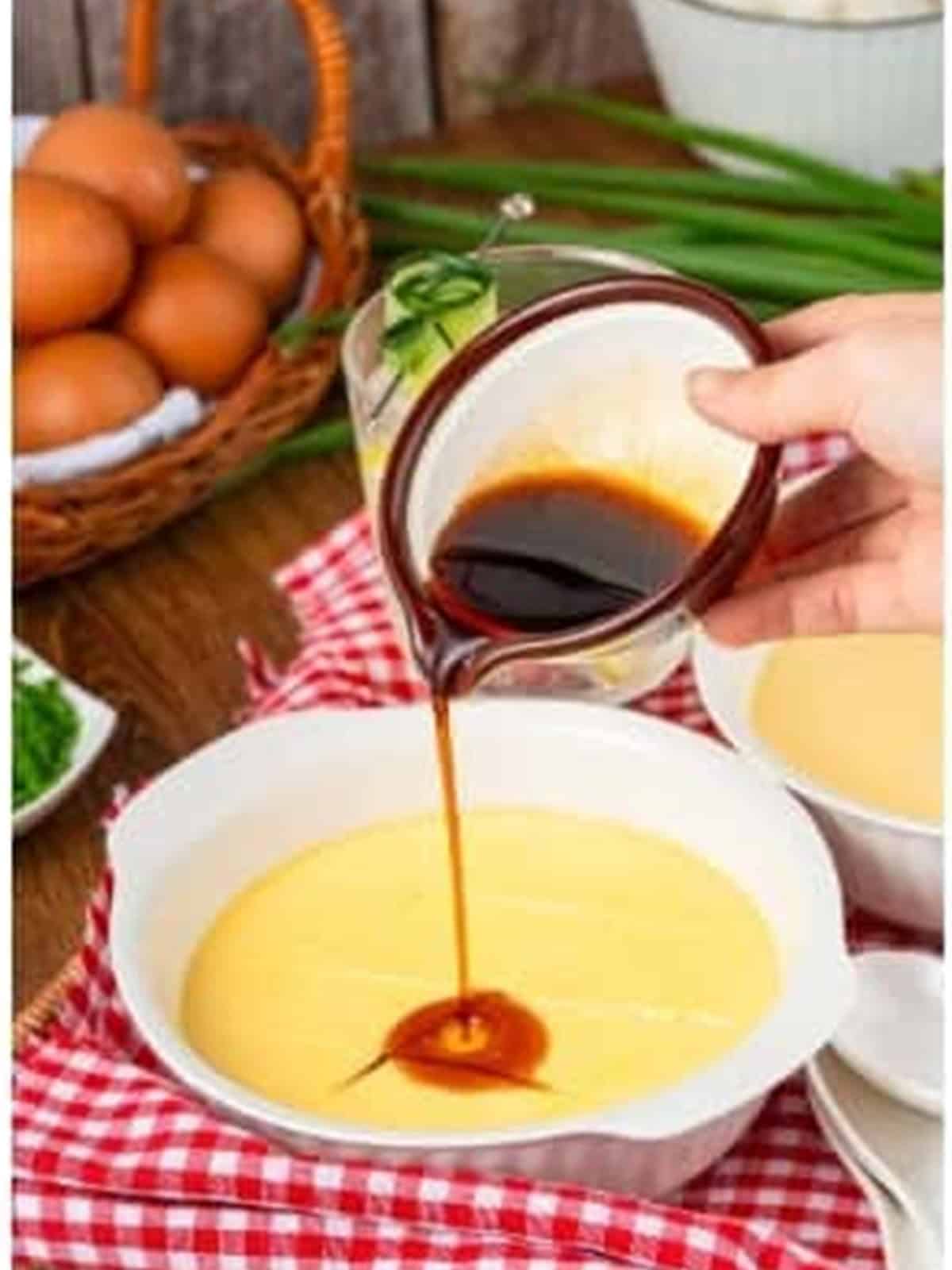 Light soy sauce being drizzled over the silky steamed eggs.
