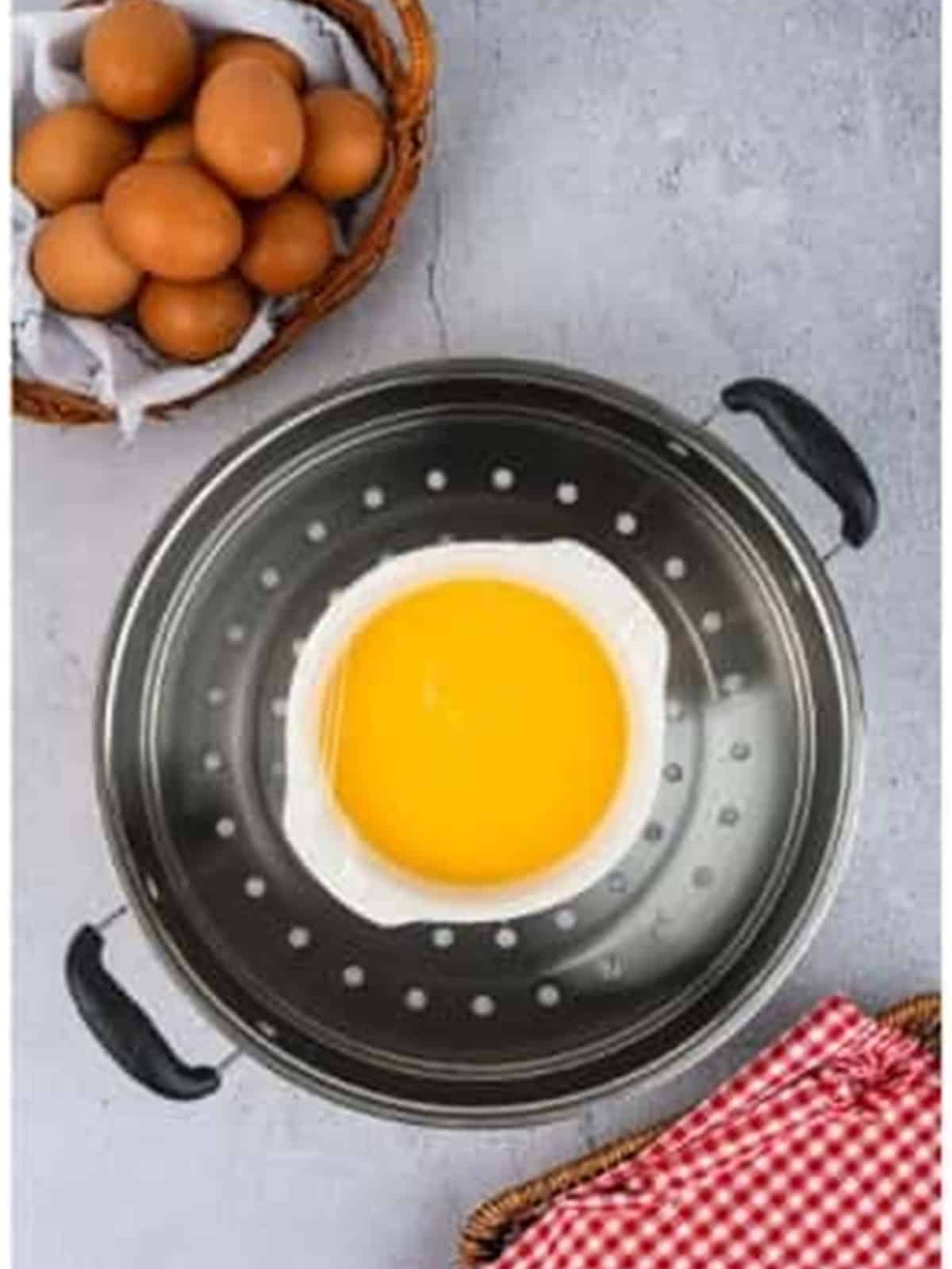 A bowl of egg mixture set on a rack inside a steamer to cook.
