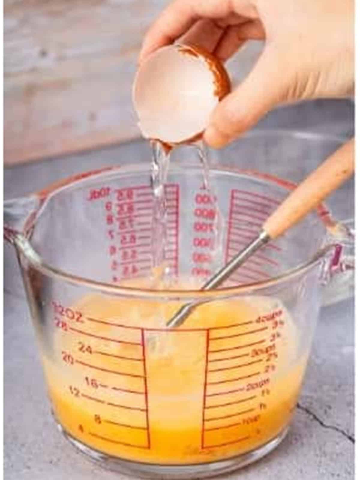 Warm water being added to the beaten eggs in the measuring bowl.