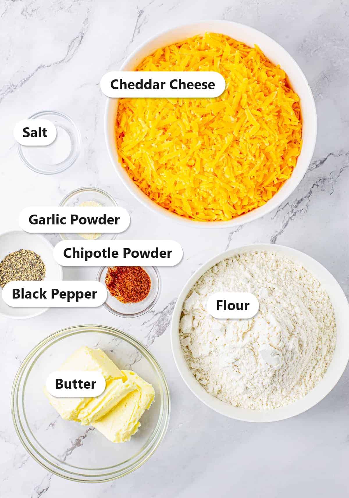 Labeled ingredients for Southern Chipotle Cheese Straws including sharp cheddar cheese, flour, butter, chipotle powder, garlic powder, salt, and pepper.