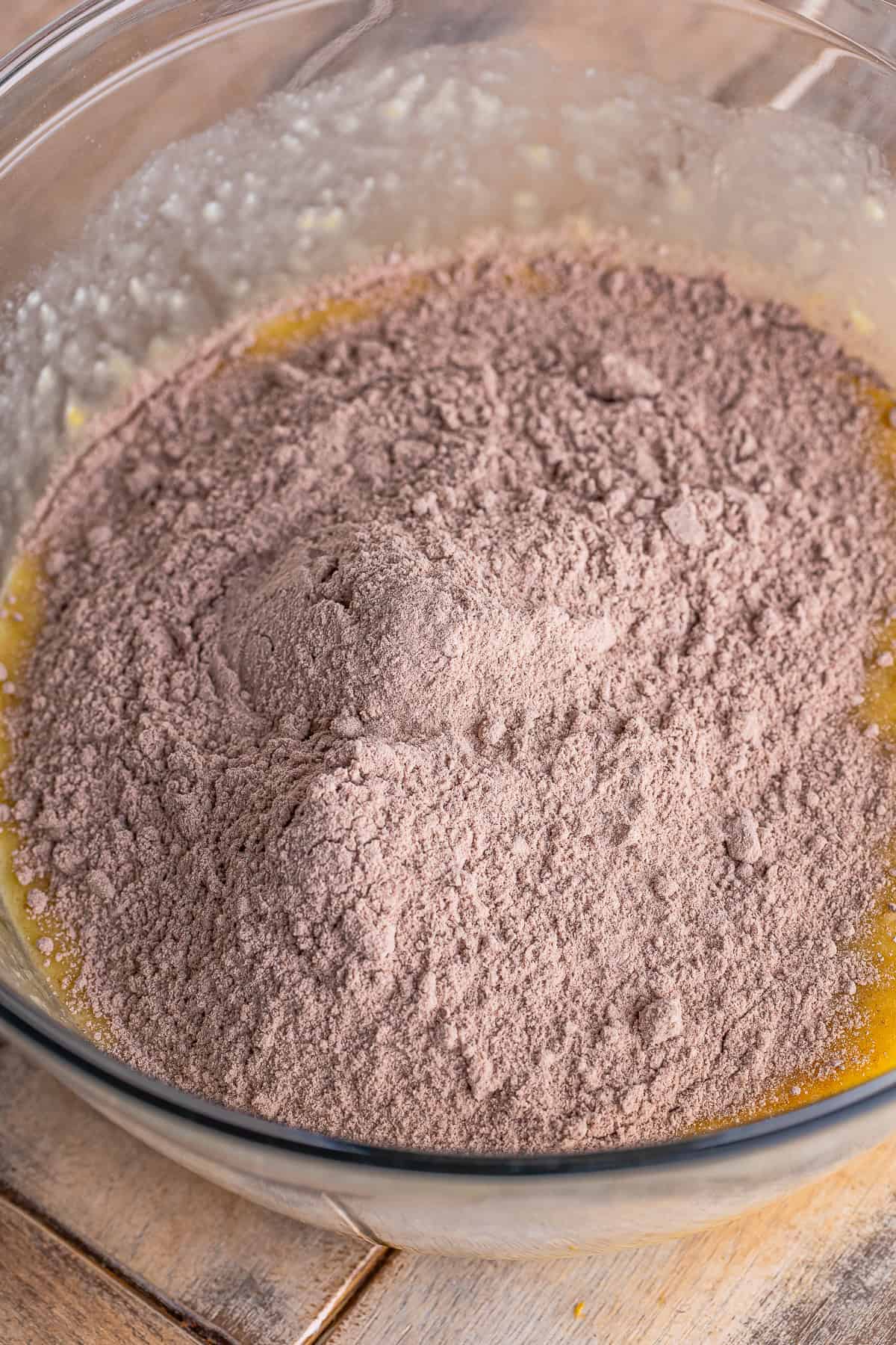 Adding chocolate cake mix to the wet banana mixture for the muffin batter.