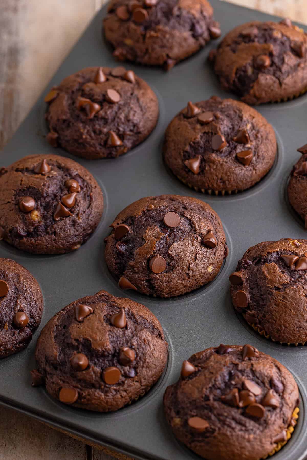 Freshly baked Banana Chocolate Chip Muffins in a muffin tin.