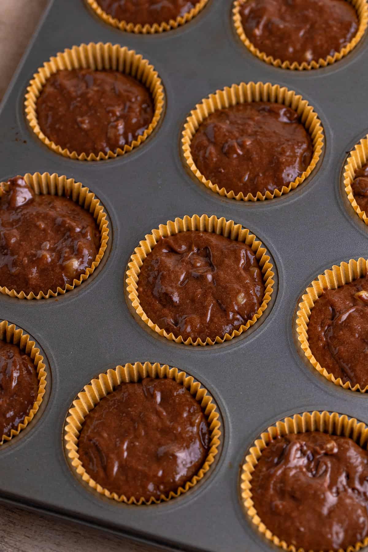 Chocolate banana muffin batter scooped into a lined muffin pan.