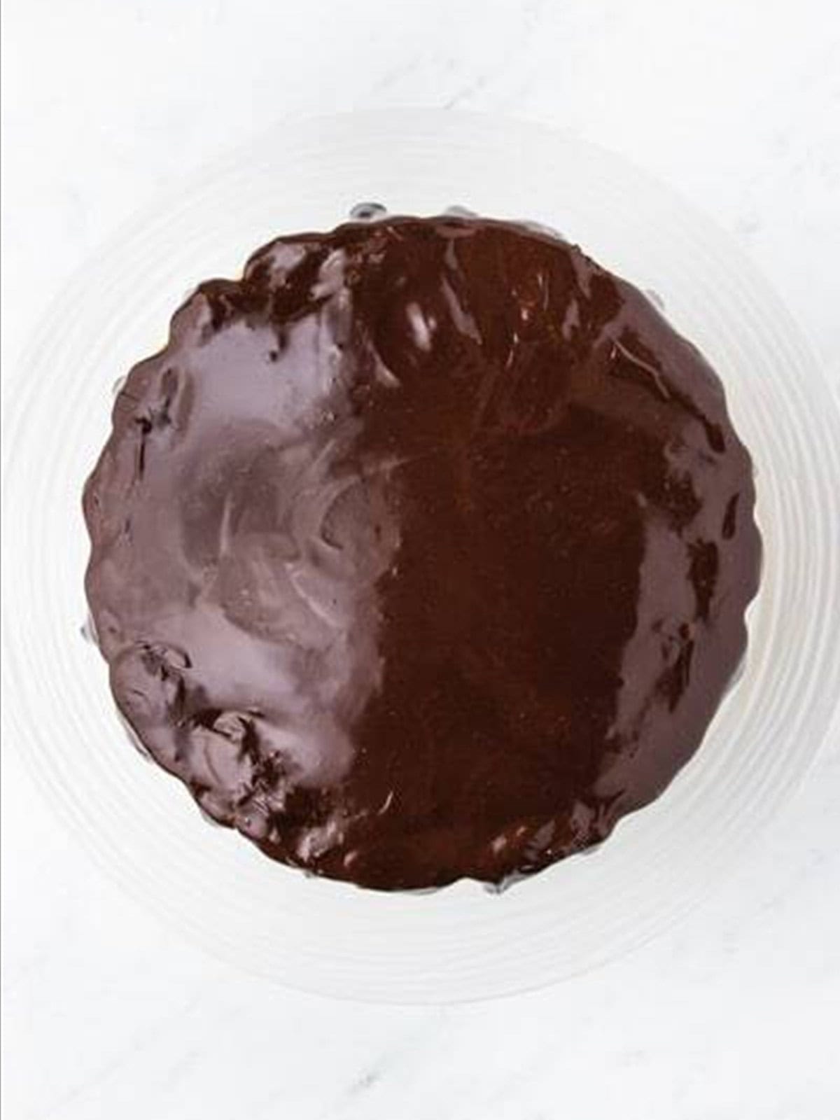 Pouring chocolate ganache over the chocolate caramel cake.
