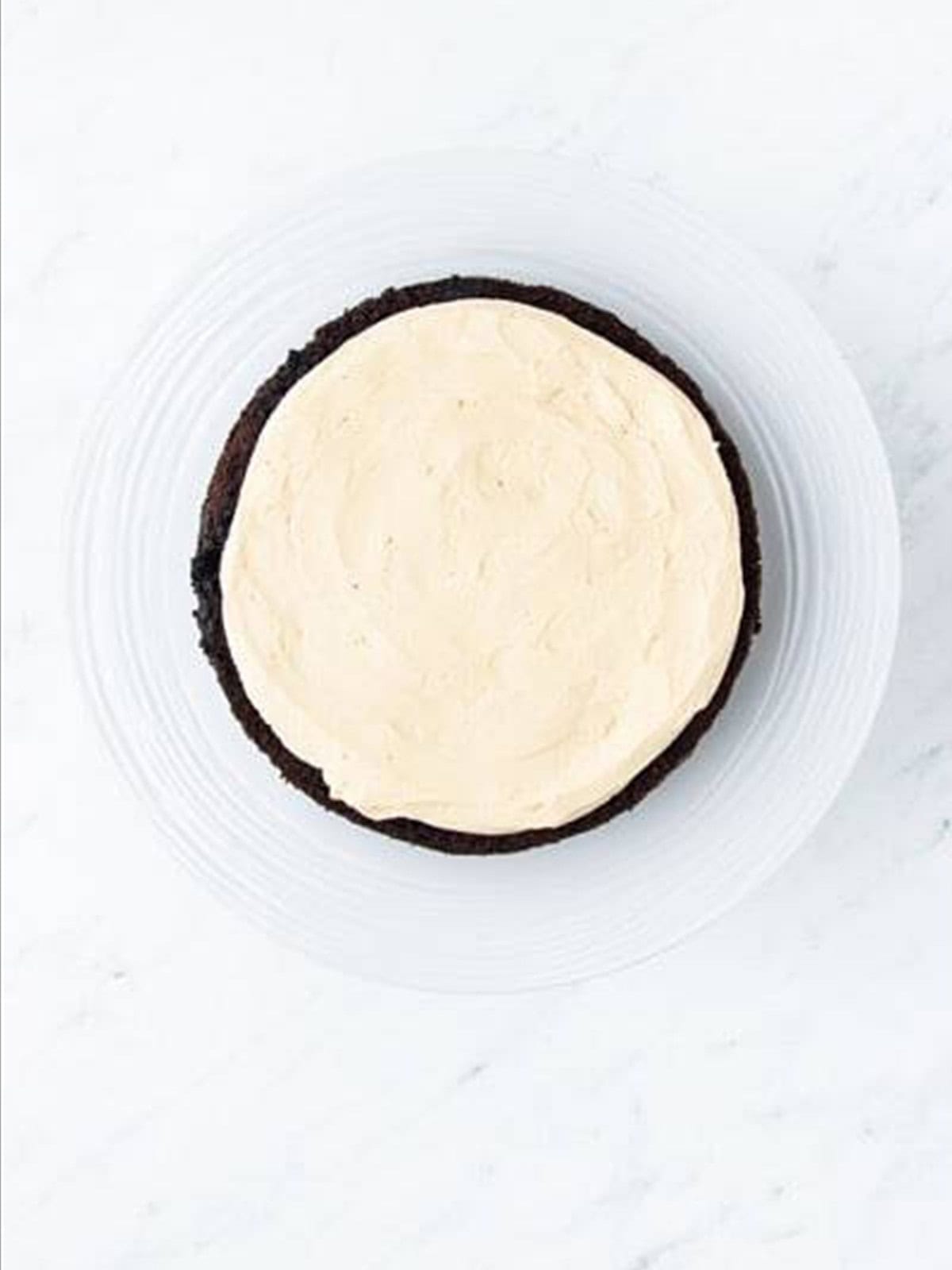 Frosting the first layer with caramel buttercream for chocolate caramel cake.