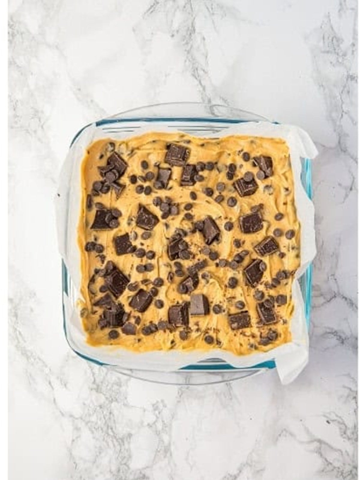 Spreading the dough in a pan and topping with chopped chocolate for Chocolate Chip Cookie Bars.