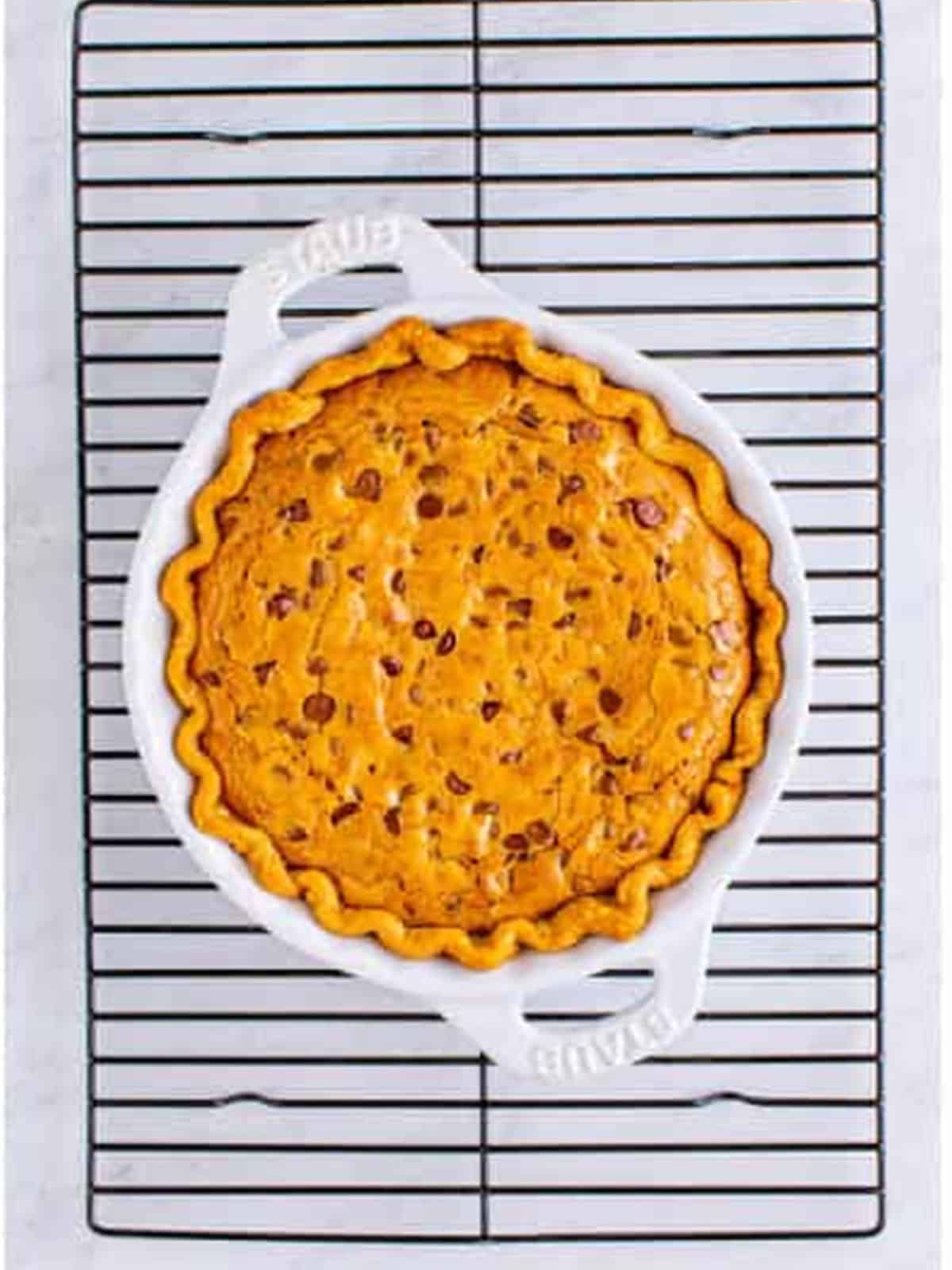 Golden baked chocolate chip cookie pie cooling on a wire rack.
