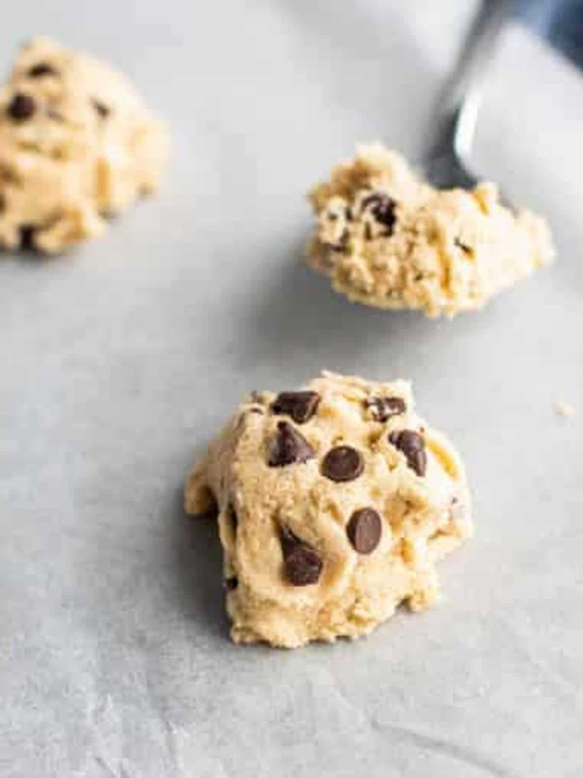 Tablespoon-sized dough balls scooped onto parchment for Chocolate Chip Cookie Sandwiches.