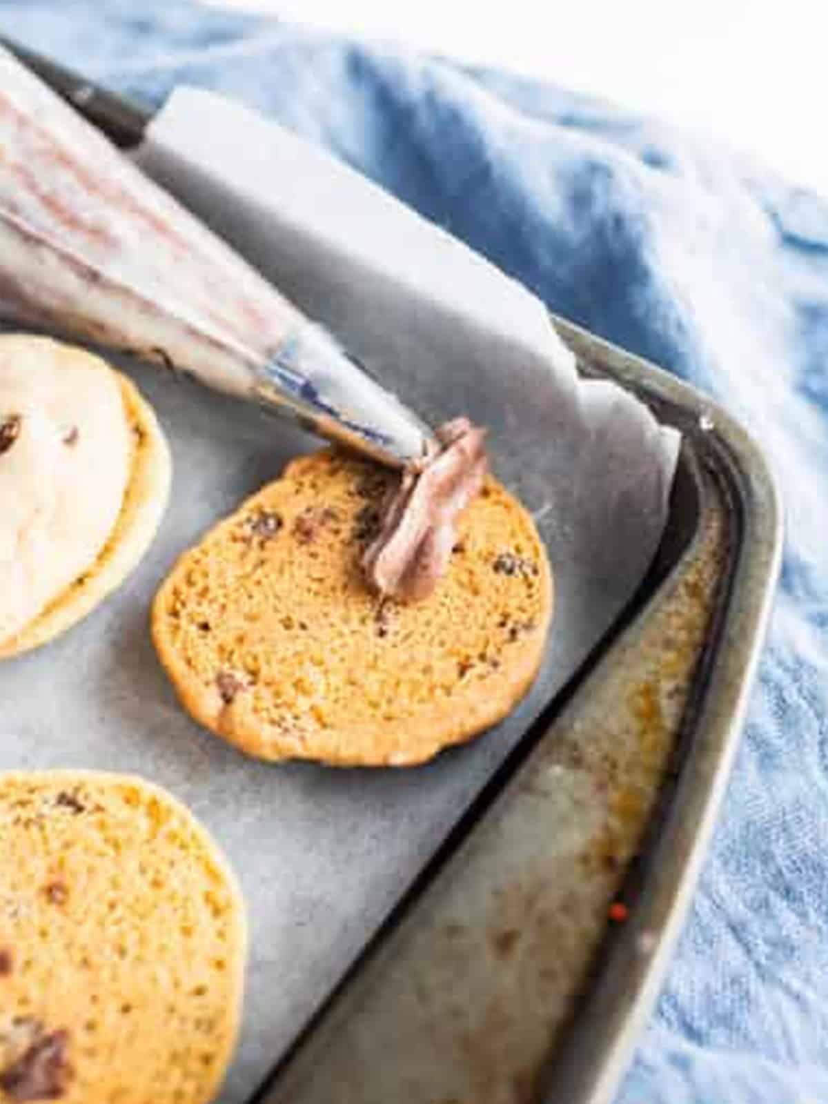 Chocolate buttercream piped onto a cookie for Chocolate Chip Cookie Sandwiches.