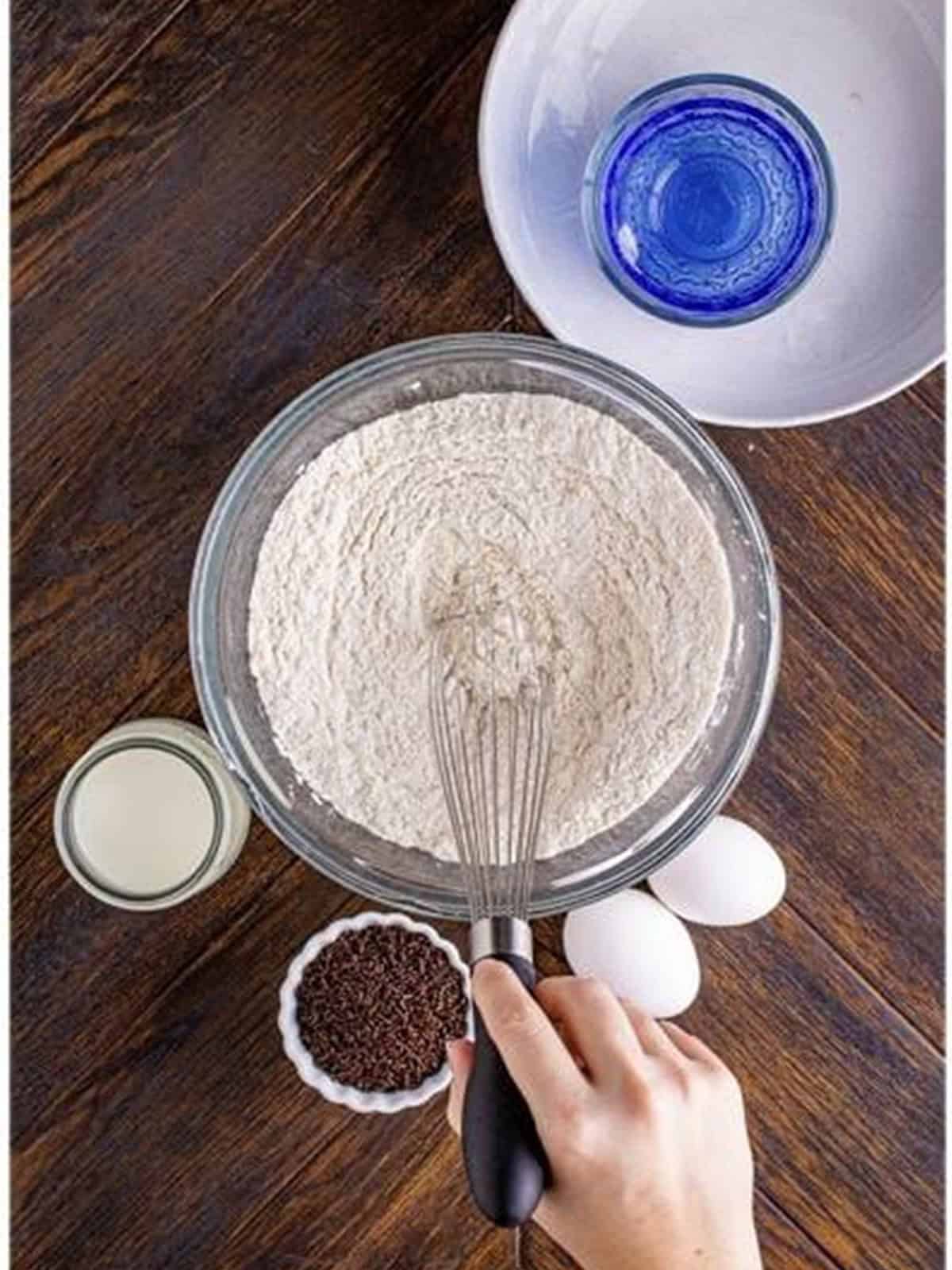 Whisking together the dry ingredients for baked chocolate chip donuts in a bowl.
