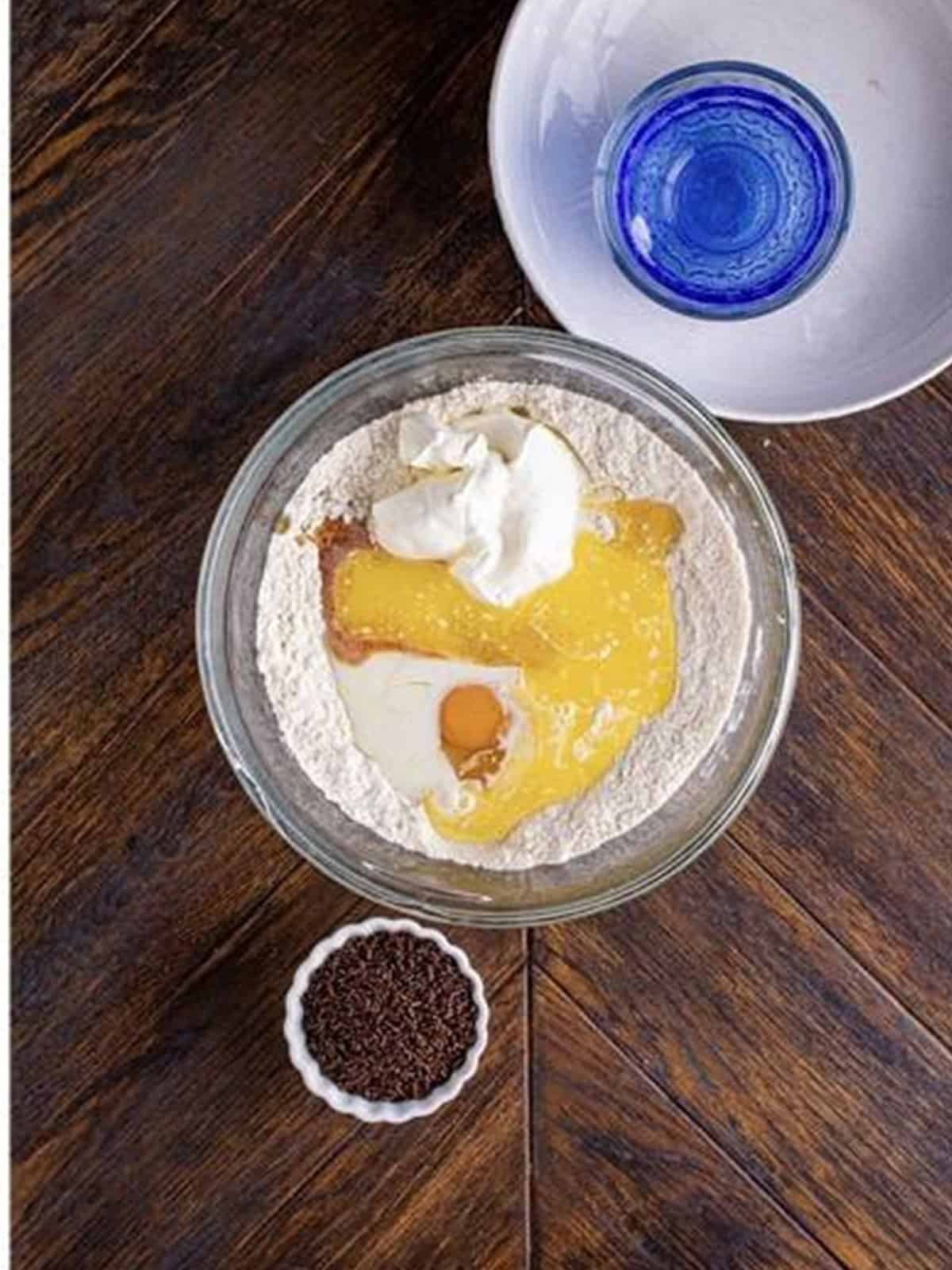 Adding eggs, sour cream, milk, and butter to the dry donut ingredients.