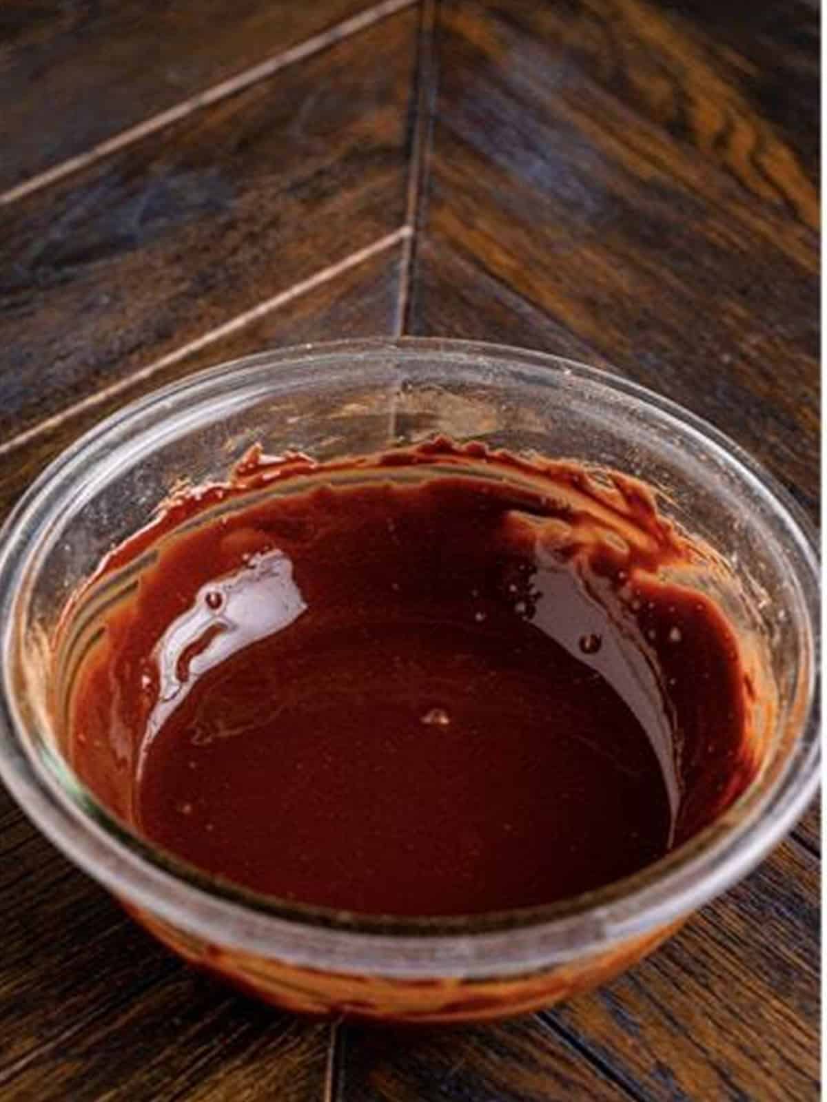 Smooth chocolate glaze whisked together in a glass bowl.