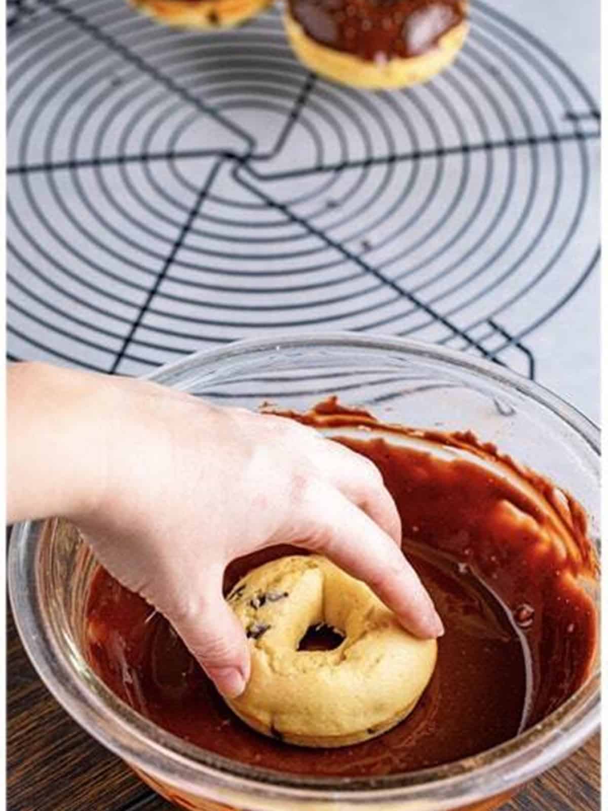 Dipping a baked chocolate chip donut into chocolate glaze.