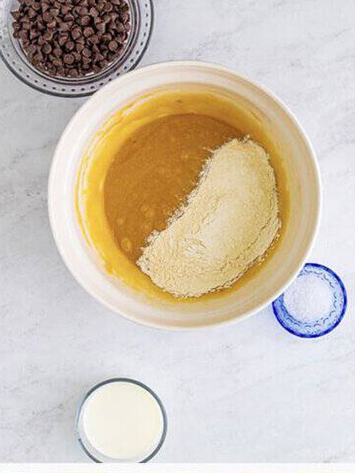 Flour mixture being added to the wet muffin batter in a bowl.