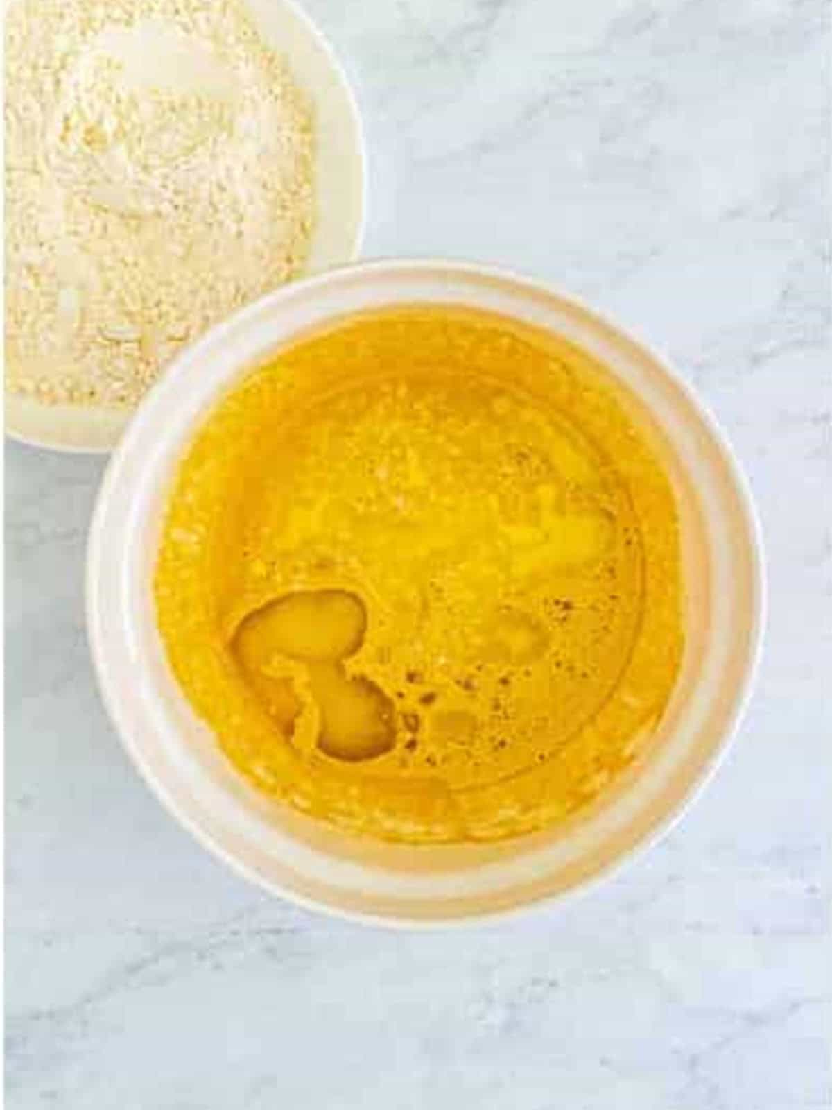 Melted butter cooling in a glass bowl.