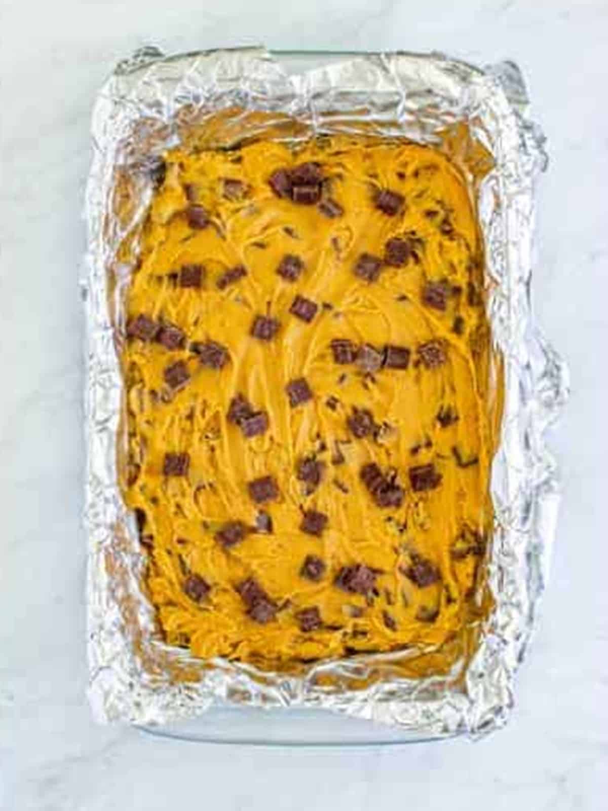 Blondie batter spread into a parchment-lined baking dish.