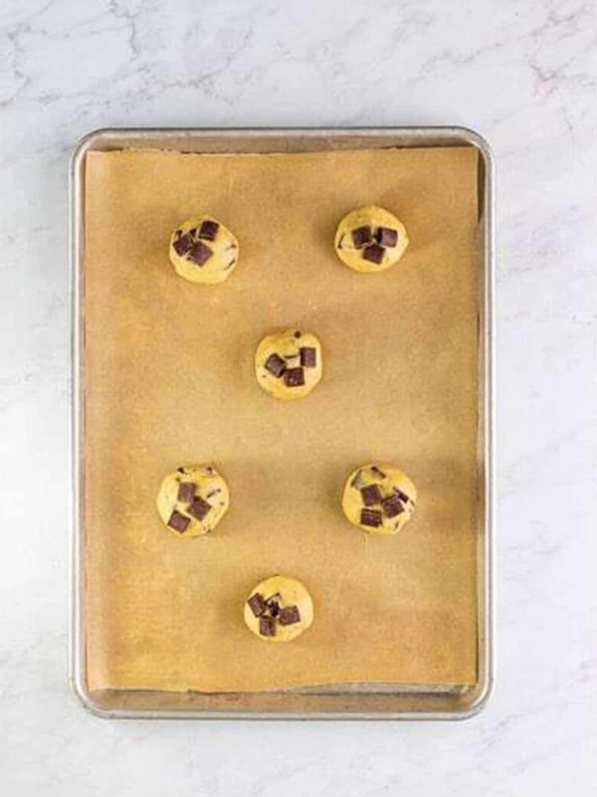 Cookie dough balls topped with extra chocolate chunks before baking.