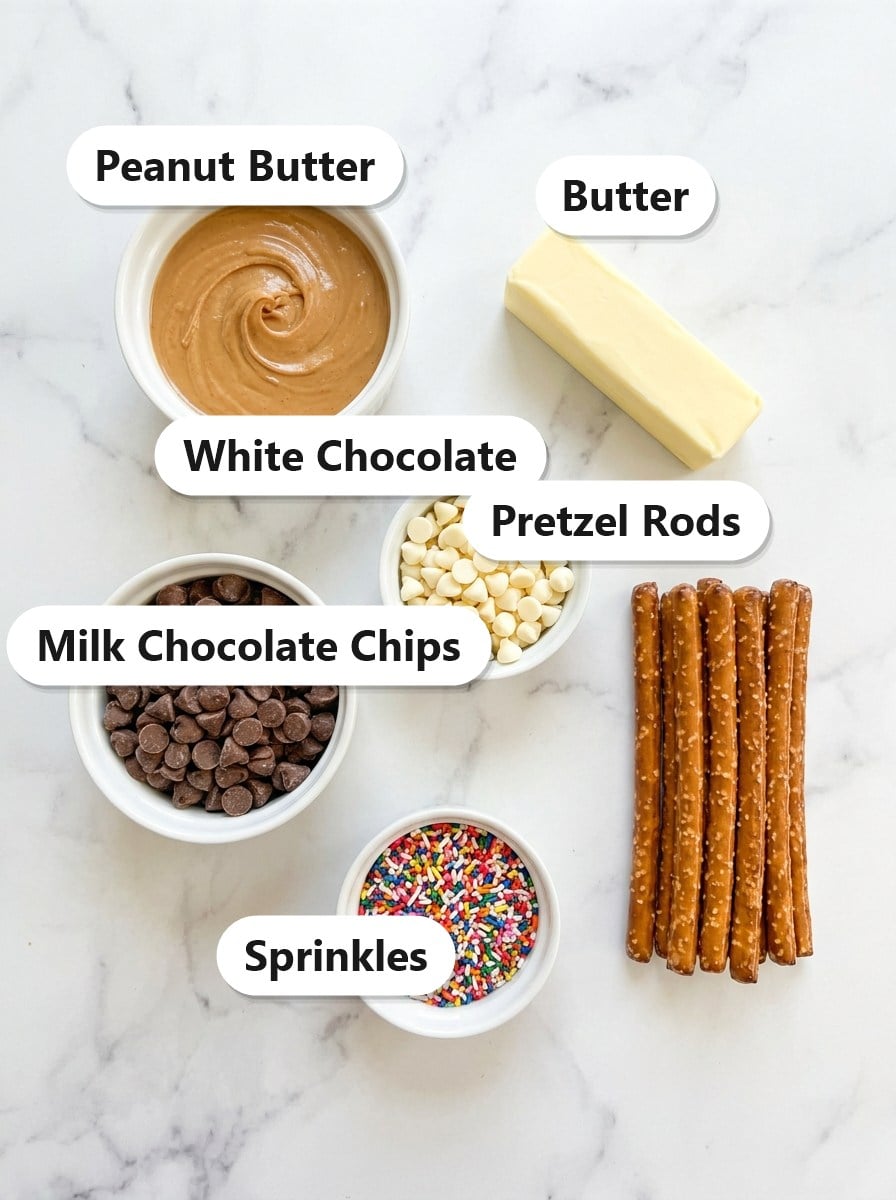 Labeled ingredients for chocolate covered peanut butter pretzels including peanut butter, butter, milk chocolate chips, white chocolate, pretzel rods, and sprinkles.