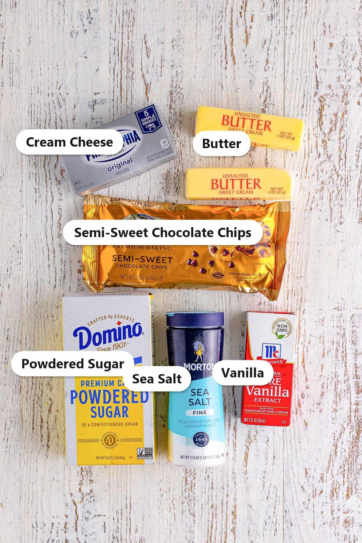 Labeled ingredients for chocolate cream cheese frosting including cream cheese, butter, semi-sweet chocolate chips, powdered sugar, sea salt, and vanilla.