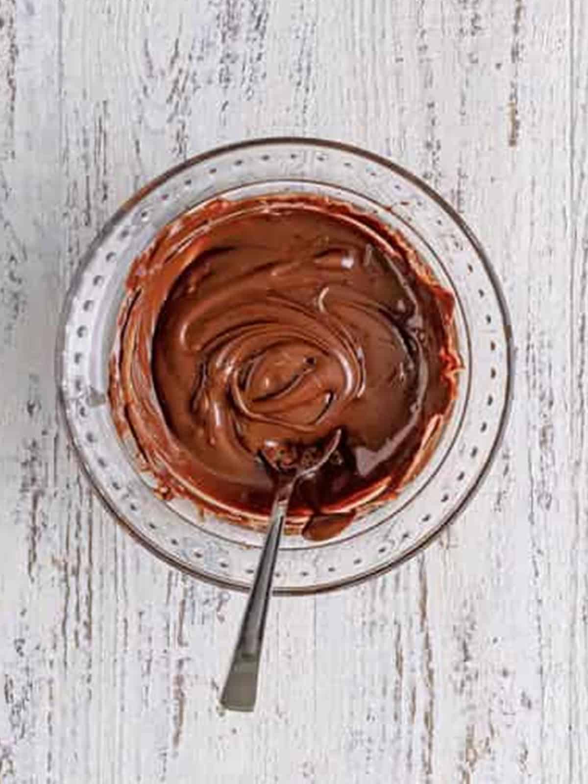 Melted semi-sweet chocolate in a small bowl for chocolate cream cheese frosting.