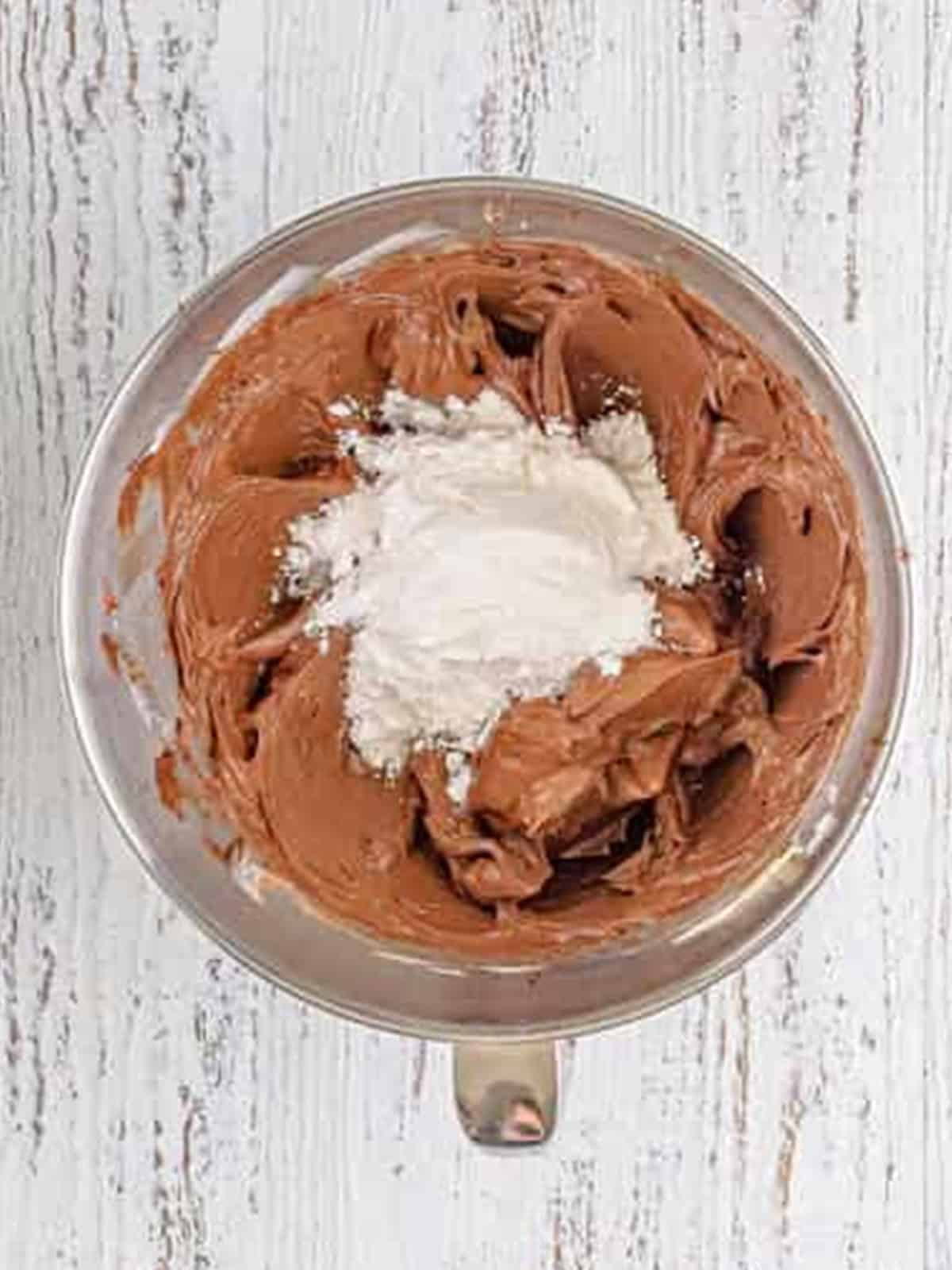 Powdered sugar added to the chocolate cream cheese frosting in the mixer.