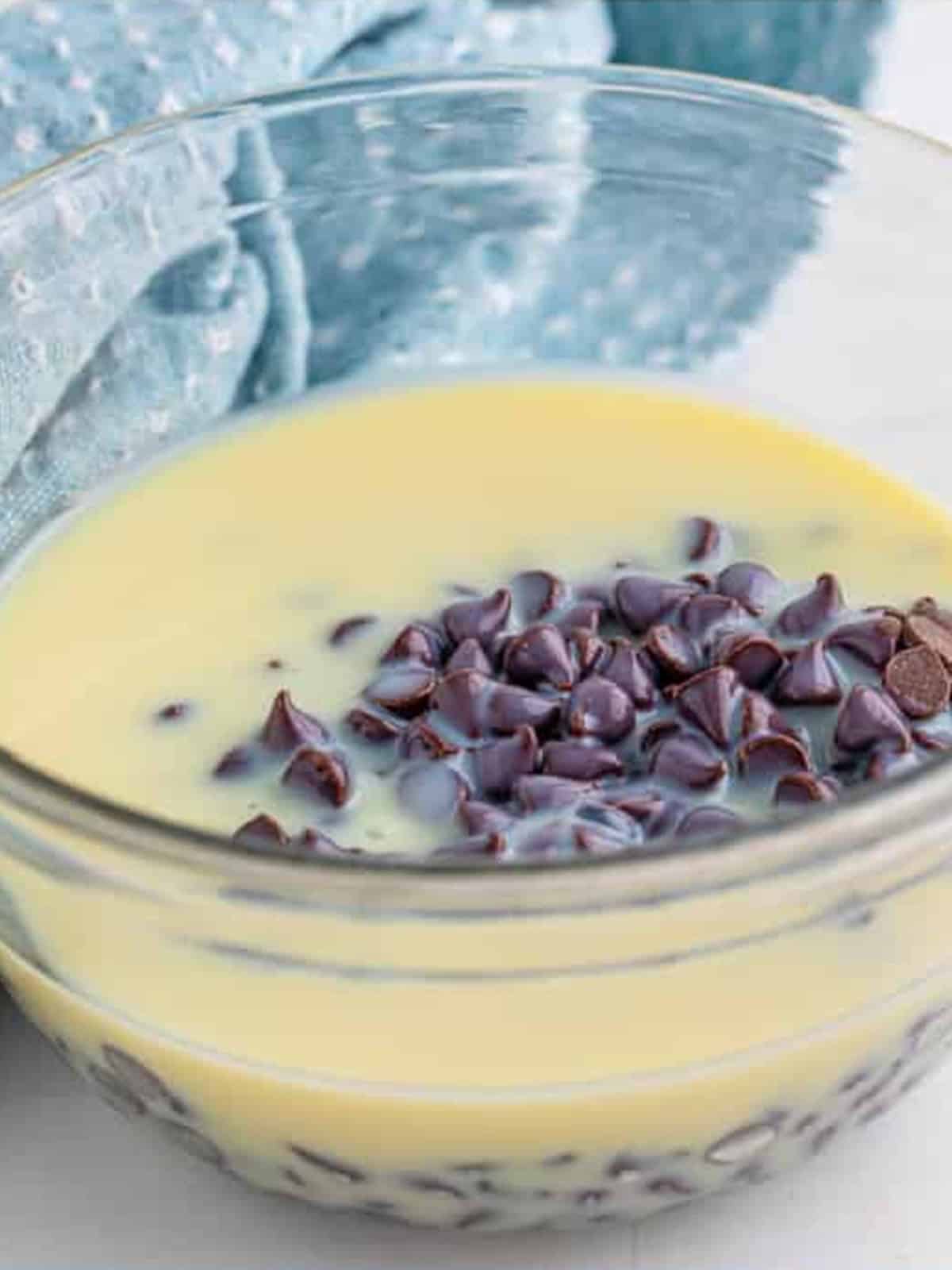 Chocolate chips and sweetened condensed milk in a bowl before melting for chocolate fudge.