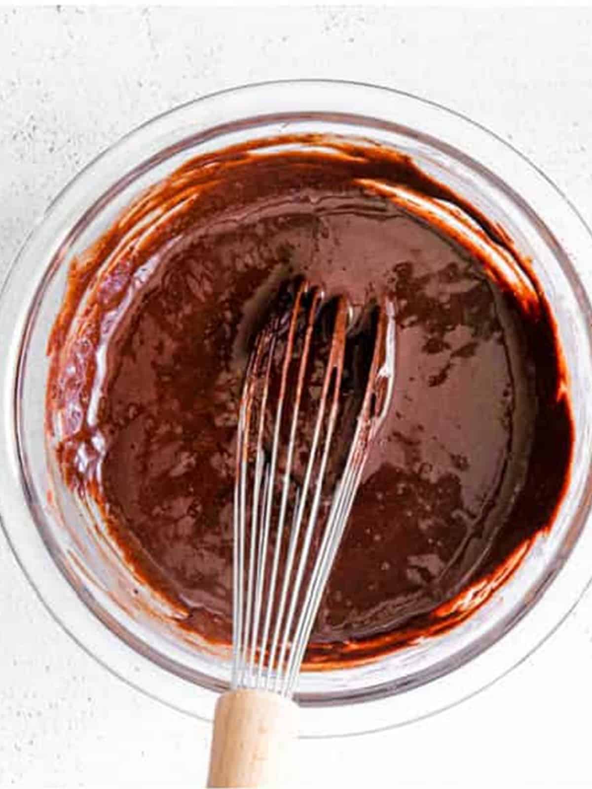 Melted chocolate whisked with cocoa and sweetened condensed milk in a bowl.